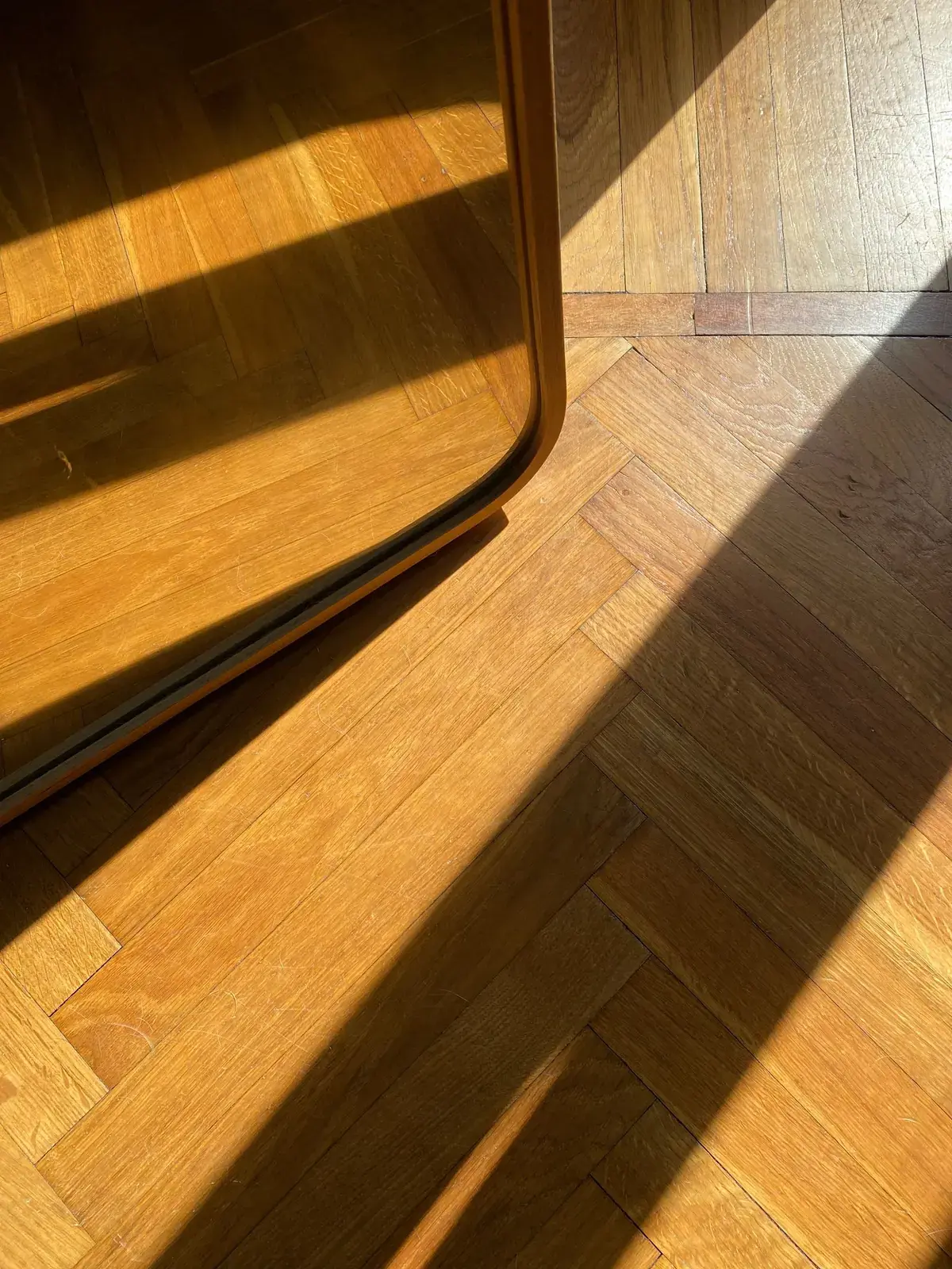 Sunlight across a herringbone wood-effect floor