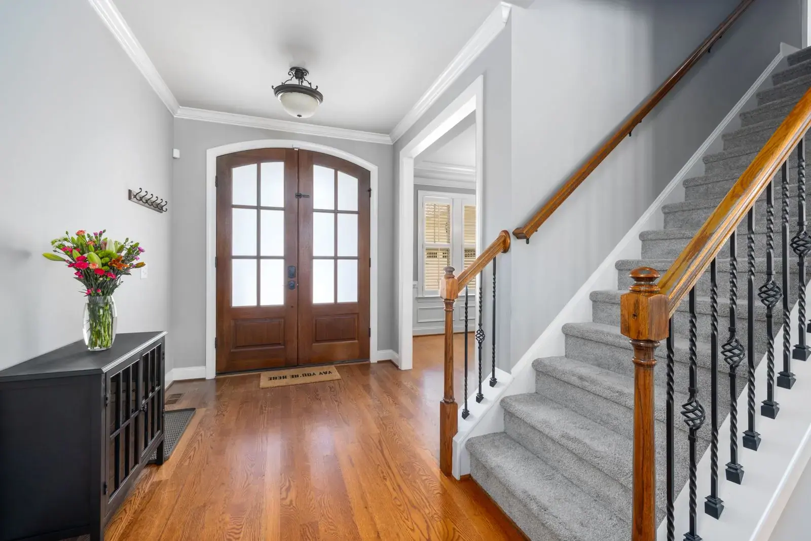 Grey carpeted staircase in a hallway with a wooden front door