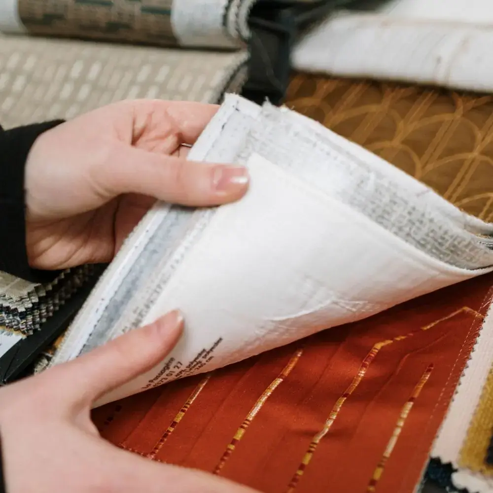 Hands turning through fabric and carpet samples